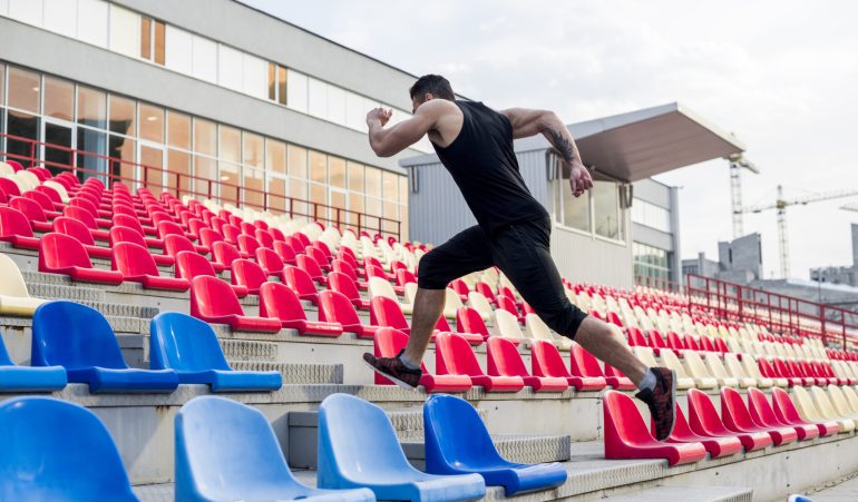 close-up-man-running-up-stairs-stadium-chairs